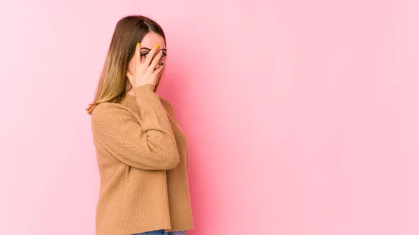 Mladá Běloška Izolovaná Růžovém Pozadí Bliká Kameru Skrz Prsty Rozpačitá — Stock fotografie