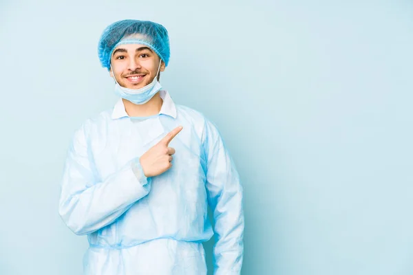 Молодий Арабський Хірург Ізольований Синьому Фоні Посміхаючись Вказуючи Вбік Показуючи — стокове фото