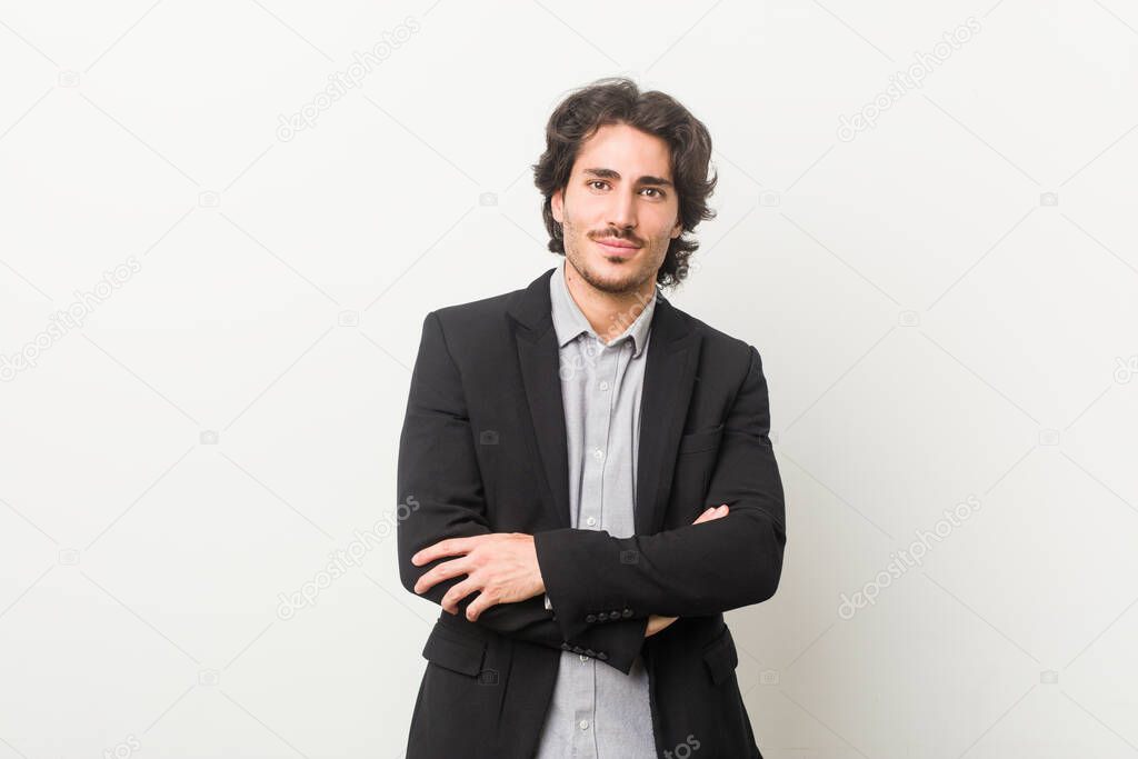 Young business man against a white background who feels confident, crossing arms with determination.