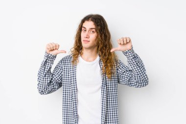 Uzun saçlı yalnız poz veren genç adam kendini gururlu ve kendinden emin hissediyor, örnek olarak..