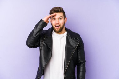 Mor arka planda izole genç adam yüksek sesle bağırıyor, gözleri açık ve elleri gergin tutuyor..