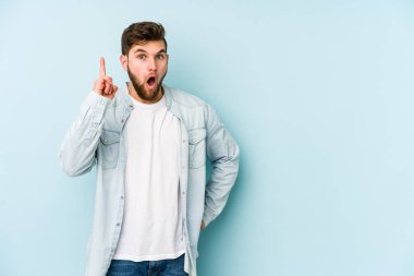 Kafkasyalı genç bir adam mavi arka planda izole edilmiş. Bir fikri, ilham verici bir fikri var..