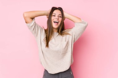 Yalnız poz veren beyaz bir kadın ellerini başının üstünde tutarak neşeli bir şekilde gülüyor. Mutluluk kavramı.