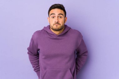 Mor arka planda izole genç beyaz adam omuzlarını silker ve gözleri açık kalır..