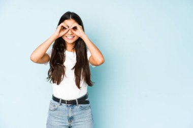 Mavi arka plandaki genç Hintli kadın gözlerinde sorun olmadığını gösteriyor.