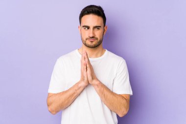 Kafkasyalı genç bir adam mor arka planda izole edilmiş bir plan yapıyor, bir fikir kuruyor..