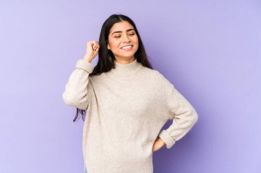 Mor arka planda izole edilmiş genç Hintli kadın zafer, tutku ve coşkuyu kutluyor, mutlu bir ifade..