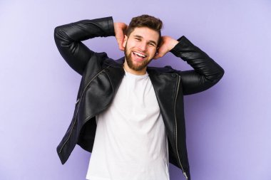 Mor arka planda izole edilmiş genç bir adam. Kolları esnetiyor, rahat pozisyonda..