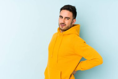 Mavi arka planda izole edilmiş beyaz bir adam sırt ağrısı çekiyor..