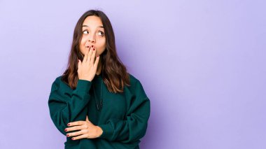 Genç, Latin kökenli bir kadın kendini izole etmiş esniyor. Ağzıyla ağzını kapatan yorgun bir hareket sergiliyor..