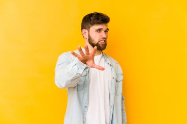 Sarı arka planda izole edilmiş genç beyaz adam tiksinti belirtisi gösteren birini reddediyor..
