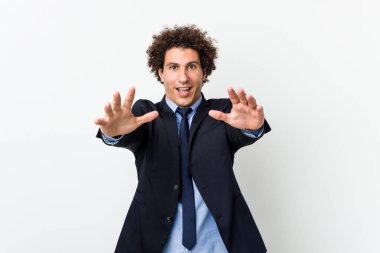 Genç iş adamı beyaz arka planda kameraya sarılırken kendine güveniyor..