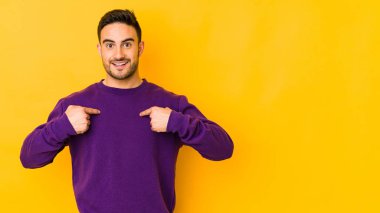 Sarı fırında izole edilmiş genç beyaz adam parmağını göstererek şaşırdı ve gülümsedi..