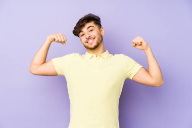 Mor arka planda izole edilmiş genç bir Arap erkek güçlü bir hareket gösteriyor, kollarıyla, kadınsı gücün sembolü.