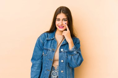 Beyaz tenli genç bir kadın bej arka planda izole edilmiş ağlıyordu, bir şeyden mutsuzdu, acı ve kafa karışıklığı içeriyordu..