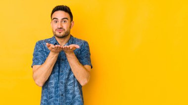 Kafkasyalı genç adam sarı fırında izole edilmiş dudak büküyor ve hava öpücüğü yollamak için avuç içi tutuyor..