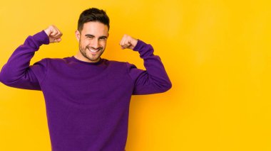 Sarı fırında izole edilmiş genç beyaz adam özel bir günü kutluyor, atlıyor ve enerjiyle kollarını kaldırıyor..