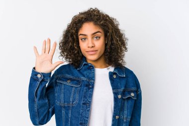 Genç Afrikalı Amerikalı kadın gülümseyerek beş numarayı parmaklarıyla gösteriyor..