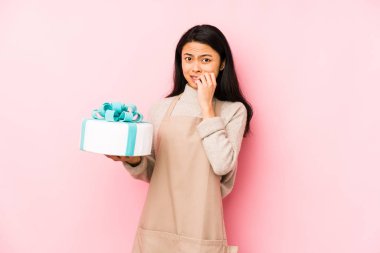 Genç Çinli bir kadın pastayı tek başına tutuyor bağırıyor ve avuç içini açık tutuyor..