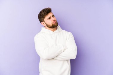 Mor arka planda izole edilmiş genç beyaz adam hedeflere ve amaçlara ulaşmayı hayal ediyor.