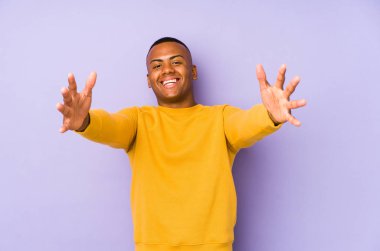 Mor arka planda izole olmuş genç Latin bir adam kameraya sarıldığı için kendinden emin hissediyor..