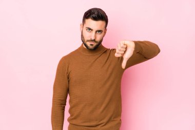 Pembe arka planda genç beyaz bir adam izole edilmiş, hoşlanmadığı bir hareket sergiliyor, reddediyor. Anlaşmazlık konsepti.