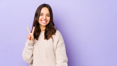 Genç, Latin kökenli, neşeli ve tasasız bir kadın parmaklarıyla barış sembolü gösteriyor..