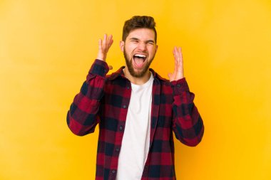 Sarı arka planda izole edilmiş genç beyaz adam yüksek sesle gülüyor ve elini göğsüne koyuyor..