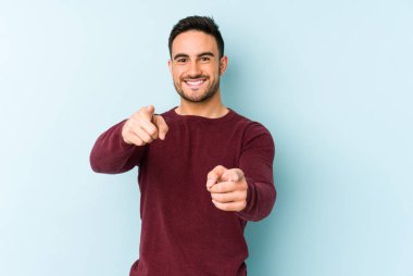 Mavi arka planda izole edilmiş genç beyaz adam öne bakan neşeli gülümsemeler.