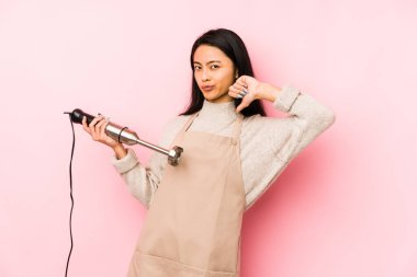 Bir mikser tutan genç Çinli kadın tırnak yiyor, gergin ve çok endişeli..