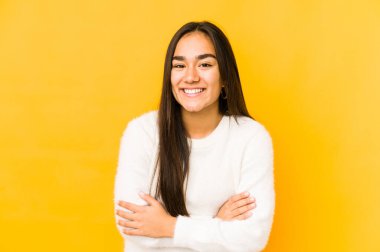 Sarı arka planda yalnız yaşayan genç bir kadın gülüyor ve eğleniyor..