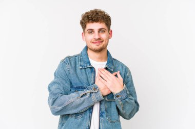 Sarışın, kıvırcık saçlı, beyaz tenli bir adam dost canlısı bir ifadeye sahip, avuçlarını göğsüne bastırıyor. Aşk konsepti.