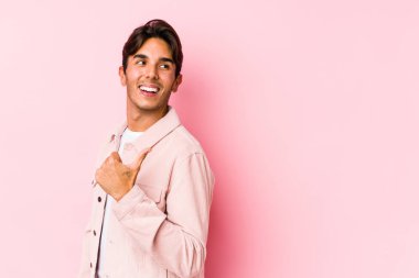 Pembe arka planda poz veren beyaz bir genç parmak uzakta, gülen ve kaygısız noktalar var..