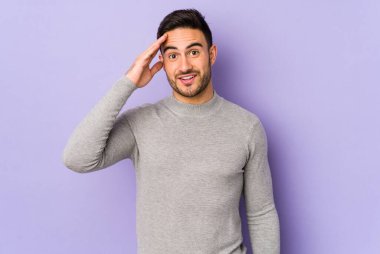 Mor arka planda izole edilmiş genç beyaz adam yüksek sesle bağırıyor, gözleri açık ve elleri gergin tutuyor..