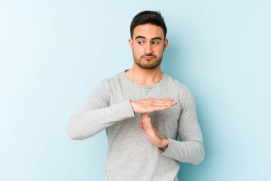 Mavi arka planda izole edilmiş genç beyaz bir adam bir mola hareketi gösteriyor..