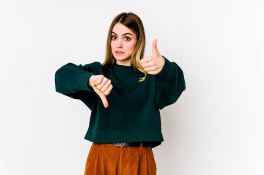 Beyaz arka planda izole edilmiş genç beyaz bir kadın baş parmağını kaldırıyor ve baş parmağını aşağı gösteriyor, zor seçim konsepti.