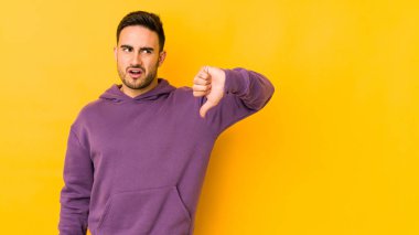 Sarı fırında izole edilmiş genç beyaz bir adam baş parmağını aşağı gösteriyor ve hoşlanmadığını ifade ediyor..