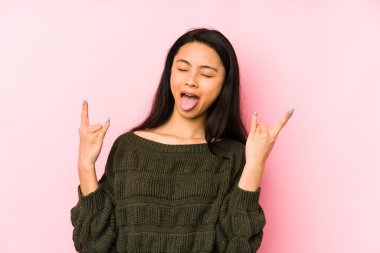 Pembe arka planda izole edilmiş genç Çinli kadın parmaklarıyla taş hareketi gösteriyor.