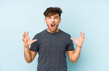 Genç Arap adam mavi arka planda izole edilmiş öfkeyle bağırıyor..