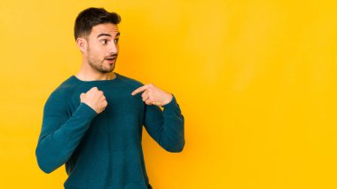 Sarı fırında izole edilmiş genç beyaz adam parmağını göstererek şaşırdı ve gülümsedi..