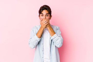Pembe arka planda poz veren beyaz bir genç, elleri ile ağzını kapatarak şoka girdi..