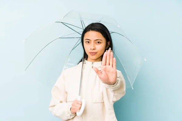 Young chinese woman holding an umbrella isolated confused, feels doubtful and unsure.