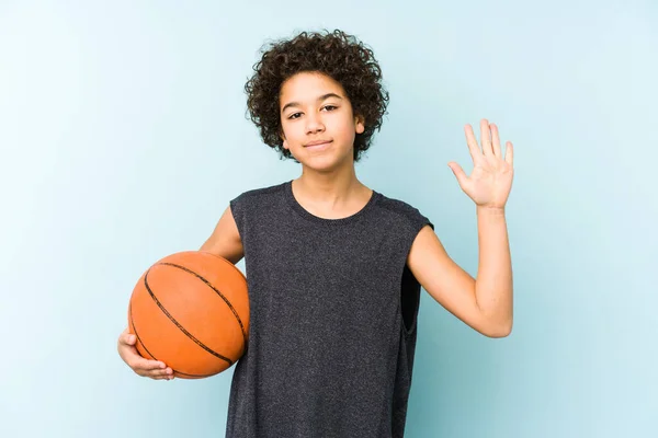 男孩在蓝色背景下孤身一人打篮球 开心地微笑着 用手指展示第五名 — 图库照片