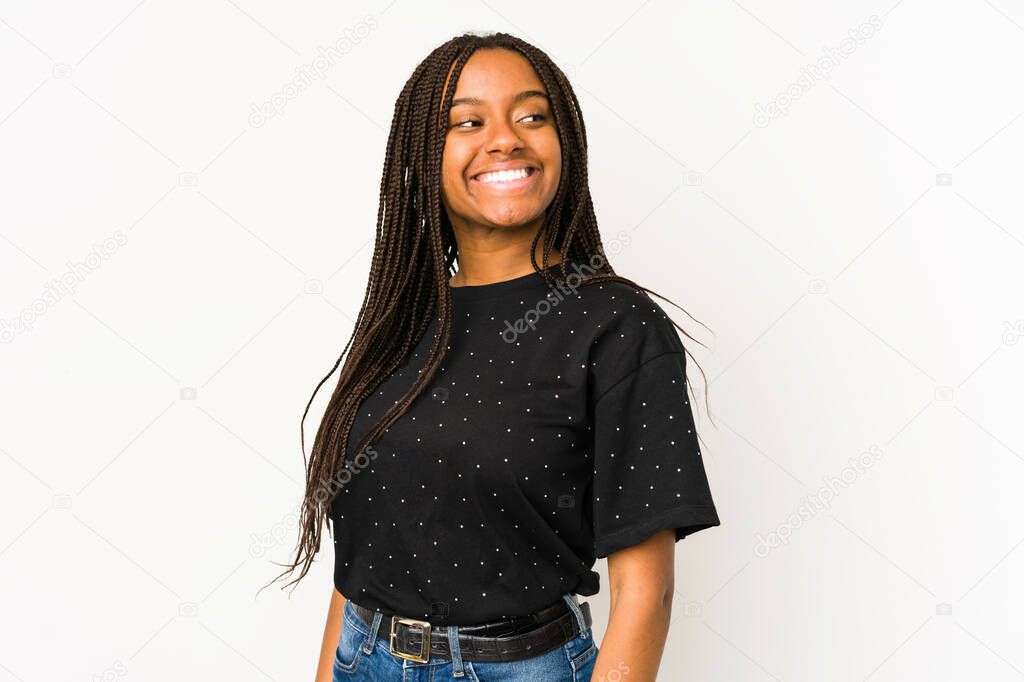 Young african american woman isolated on white background looks aside smiling, cheerful and pleasant.
