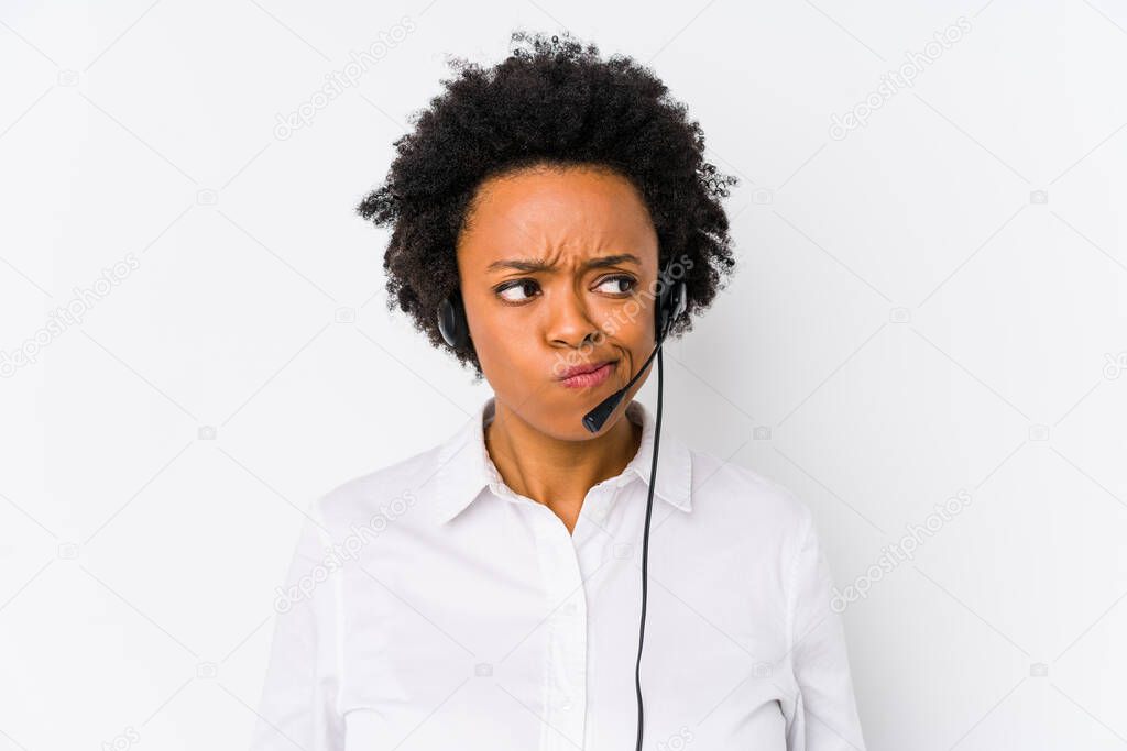 Young african american telemarketer woman isolated confused, feels doubtful and unsure.