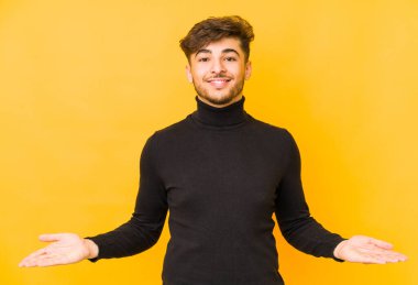 Sarı arka planda izole edilmiş genç bir Arap hoş bir ifade sergiliyor..