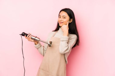 Bir mikseri tutan genç Çinli kadın hoş bir sürprizle karşılaşıyor, heyecanlı ve el kaldırıyor..