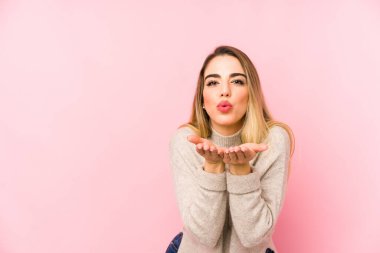 Orta yaşlı bir kadın izole edilmiş arka planda dudakları kıvrılmış ve hava öpücüğü vermek için avuç içleri tutulmuş..