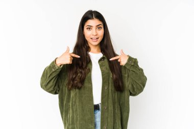 Mor arka planda izole edilmiş genç Hintli kadın parmağını göstererek şaşırdı, geniş bir gülümsemeyle..