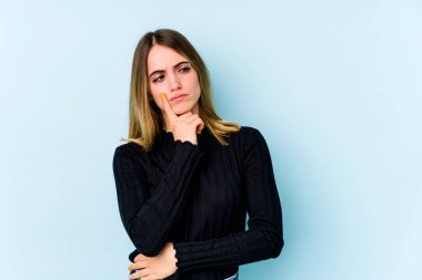 Kafkasyalı genç bir kadın, mavi arka planda izole edilmiş. Bir strateji planlıyor, bir işin nasıl olacağını düşünüyor..
